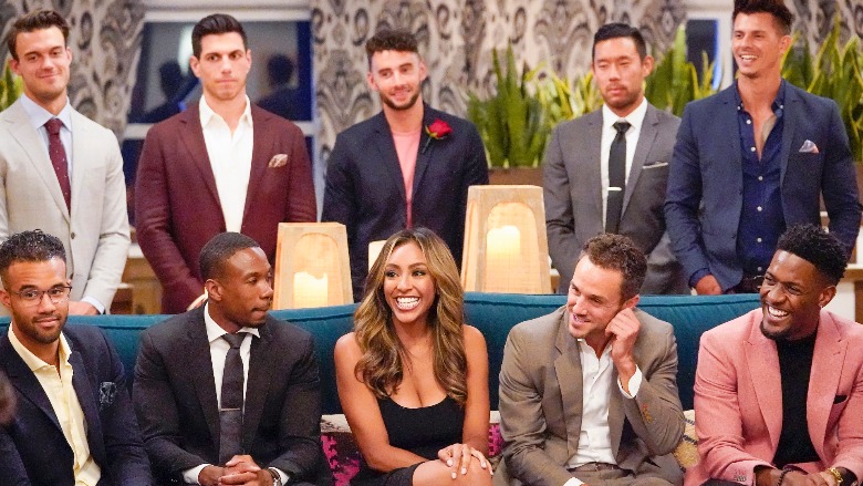 Tayshia Adams sits on a couch with a few men from her season.