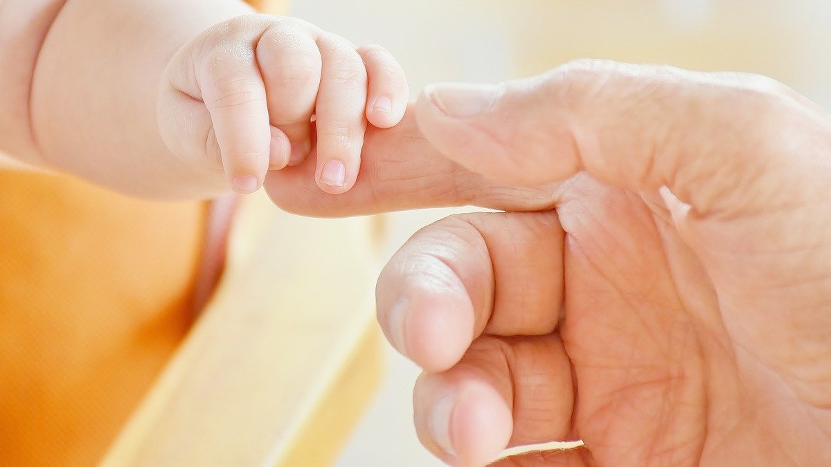 Baby and adult hold hands