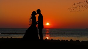 Bride and groom on beach at sunset