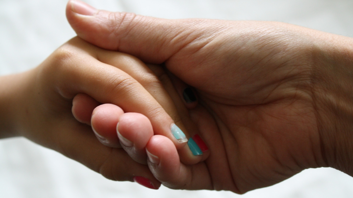 A mother holding her daughter's hand.