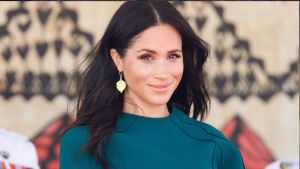 Meghan Markle pictured sitting down in a green dress with her hair blowing in the wind
