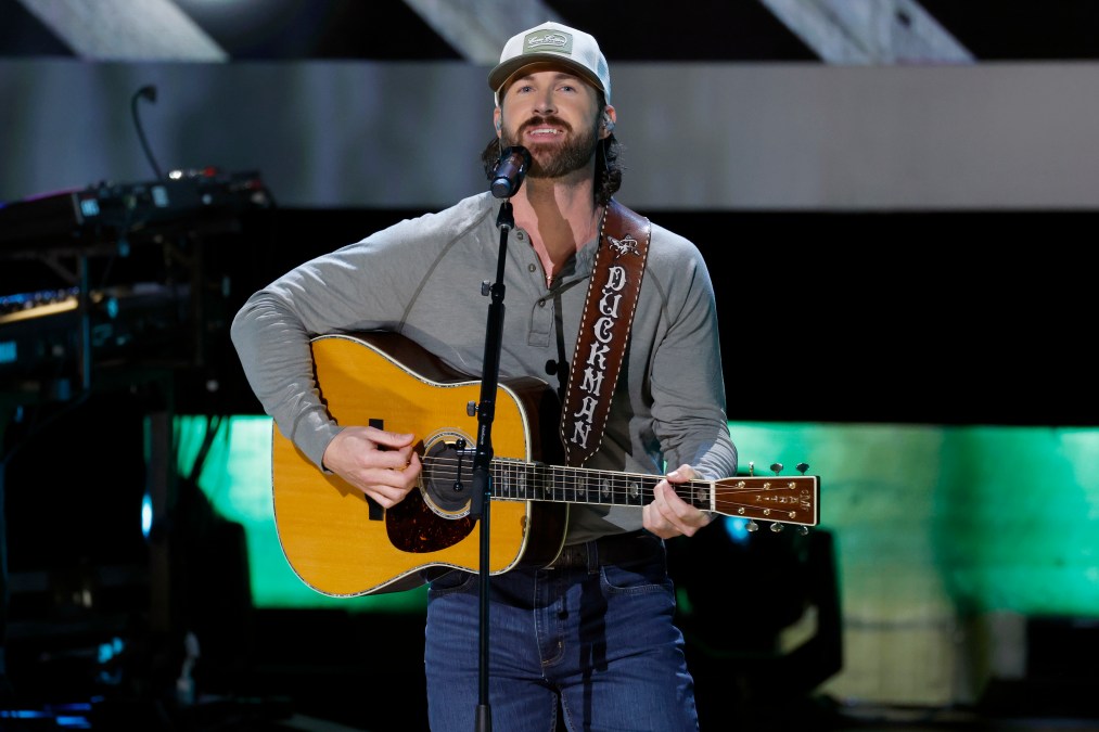 Riley Green playing guitar behind a microphone