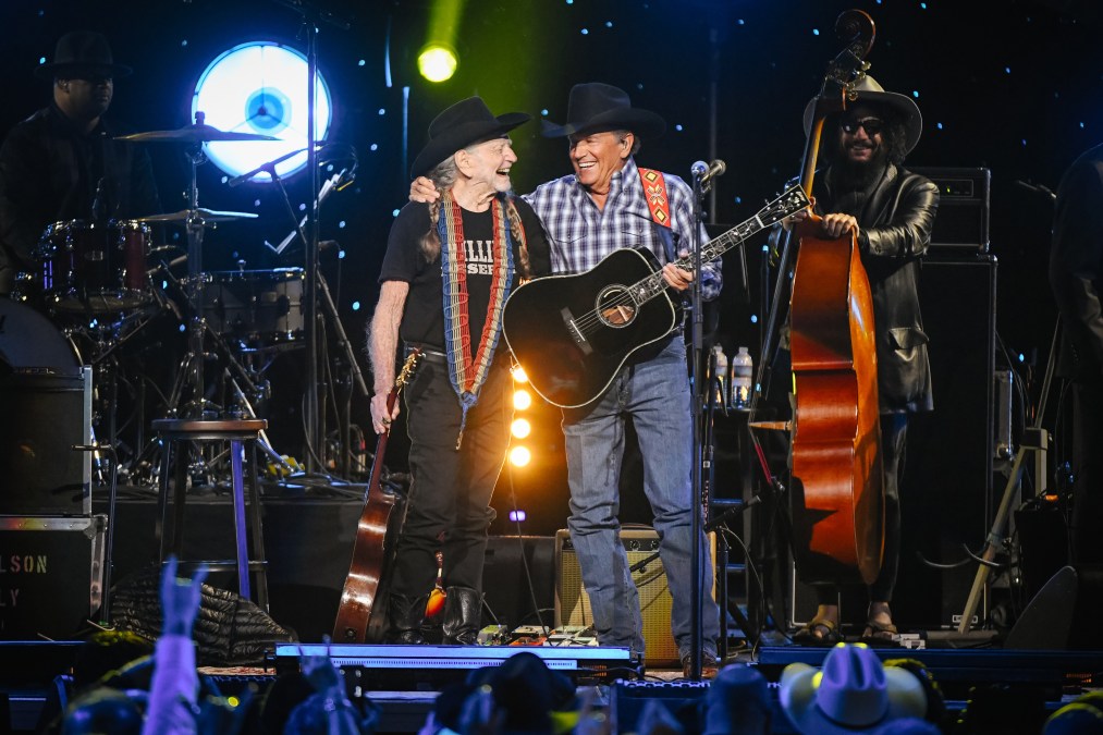 George Strait and Willie Nelson smiling on stage.