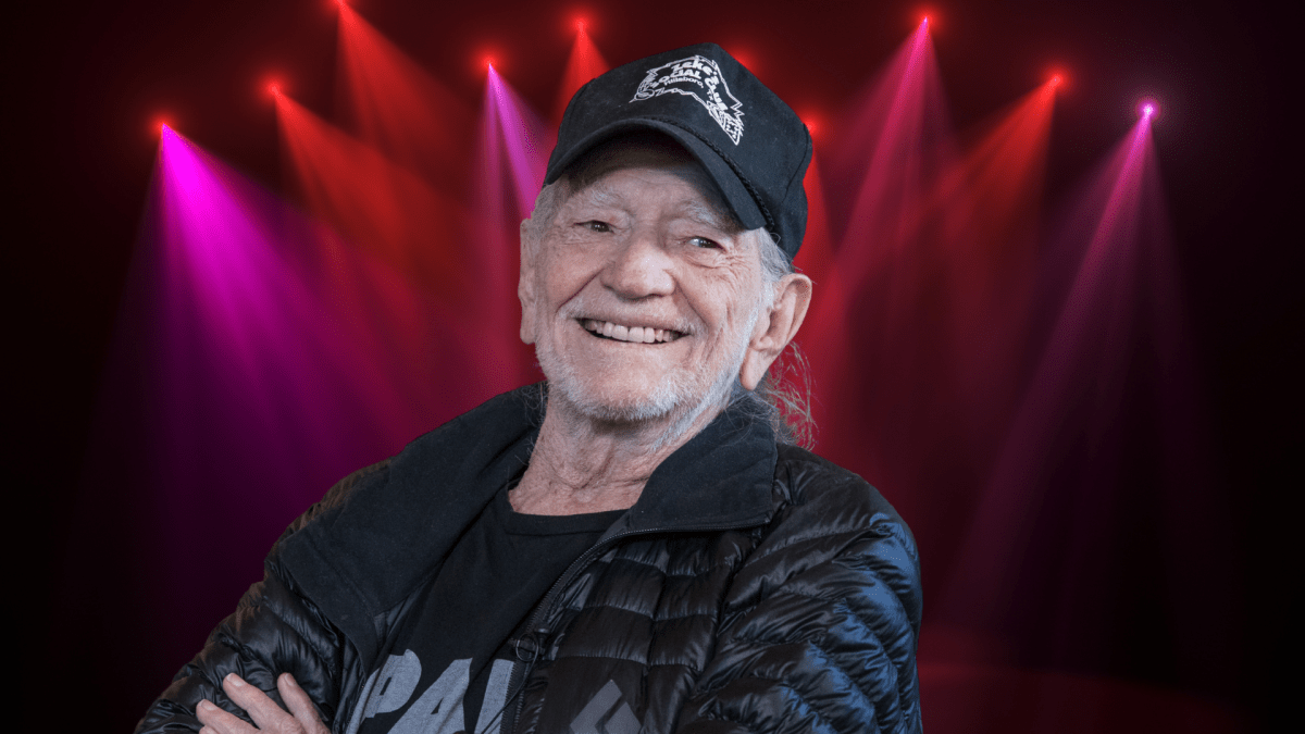 Willie Nelson smiling in front of colorful lights