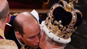 Britain's Prince William, Prince of Wales kisses his father, Britain's King Charles III, wearing St Edward's Crown, during the King's Coronation Ceremony inside Westminster Abbey