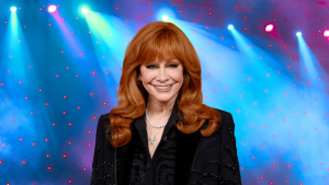Reba McEntire smiling on a colorful stage.