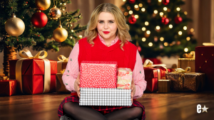 Mae Whitman holding presents wearing red vest