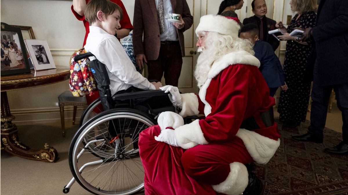 A person dressed as Father Christmas speaks with Ivan during the Christmas tree decorating event hosted by Queen Camilla, accompanied by children supported by Helen and Douglas House and Roald Dahl's, Marvellous Children's Charity, at Clarence House in London on December 11, 2025 in London, England