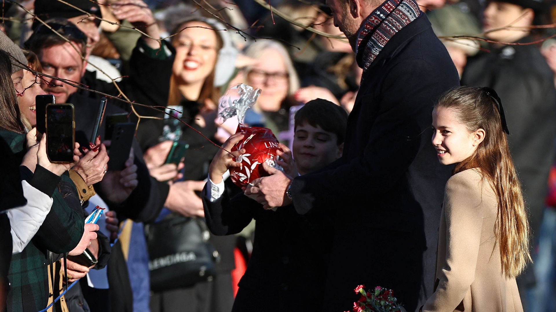 Britain's Prince Louis of Wales reacts with his father Britain's Prince William, Prince of Wales and sister Britain's Princess Charlotte of Wales as he receives a giant chocolate from a well-wisher upon leaving after attending the Royal Family's traditional Christmas Day service at St Mary Magdalene Church on the Sandringham Estate in eastern England, on December 25, 2025