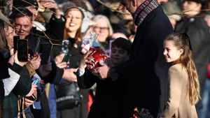 Britain's Prince Louis of Wales reacts with his father Britain's Prince William, Prince of Wales and sister Britain's Princess Charlotte of Wales as he receives a giant chocolate from a well-wisher upon leaving after attending the Royal Family's traditional Christmas Day service at St Mary Magdalene Church on the Sandringham Estate in eastern England, on December 25, 2025