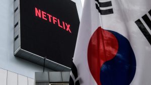 building displays the logo of Netflix beyond a South Korean flag hoisted
