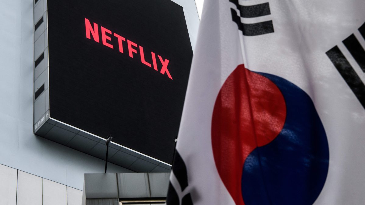building displays the logo of Netflix beyond a South Korean flag hoisted