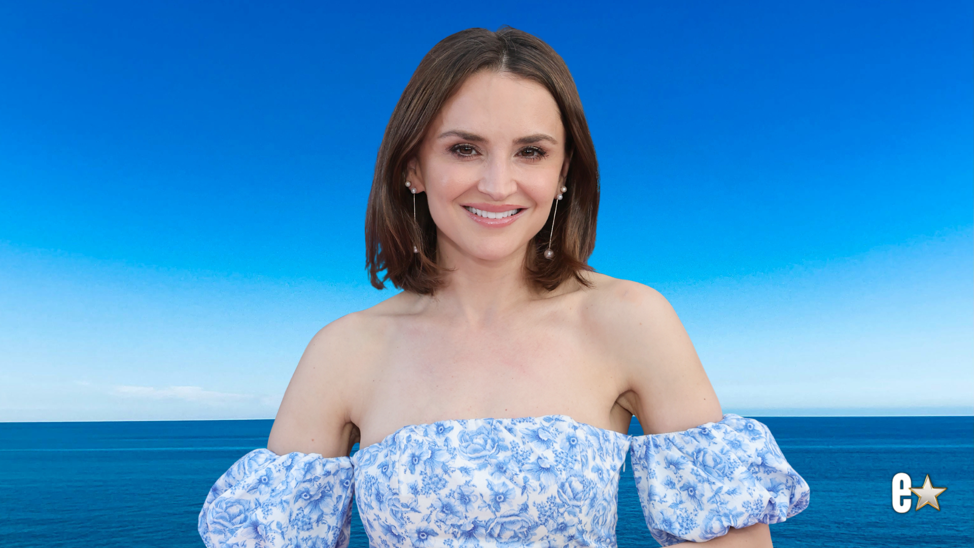 Rachael Leigh Cook smiles in blue floral dress
