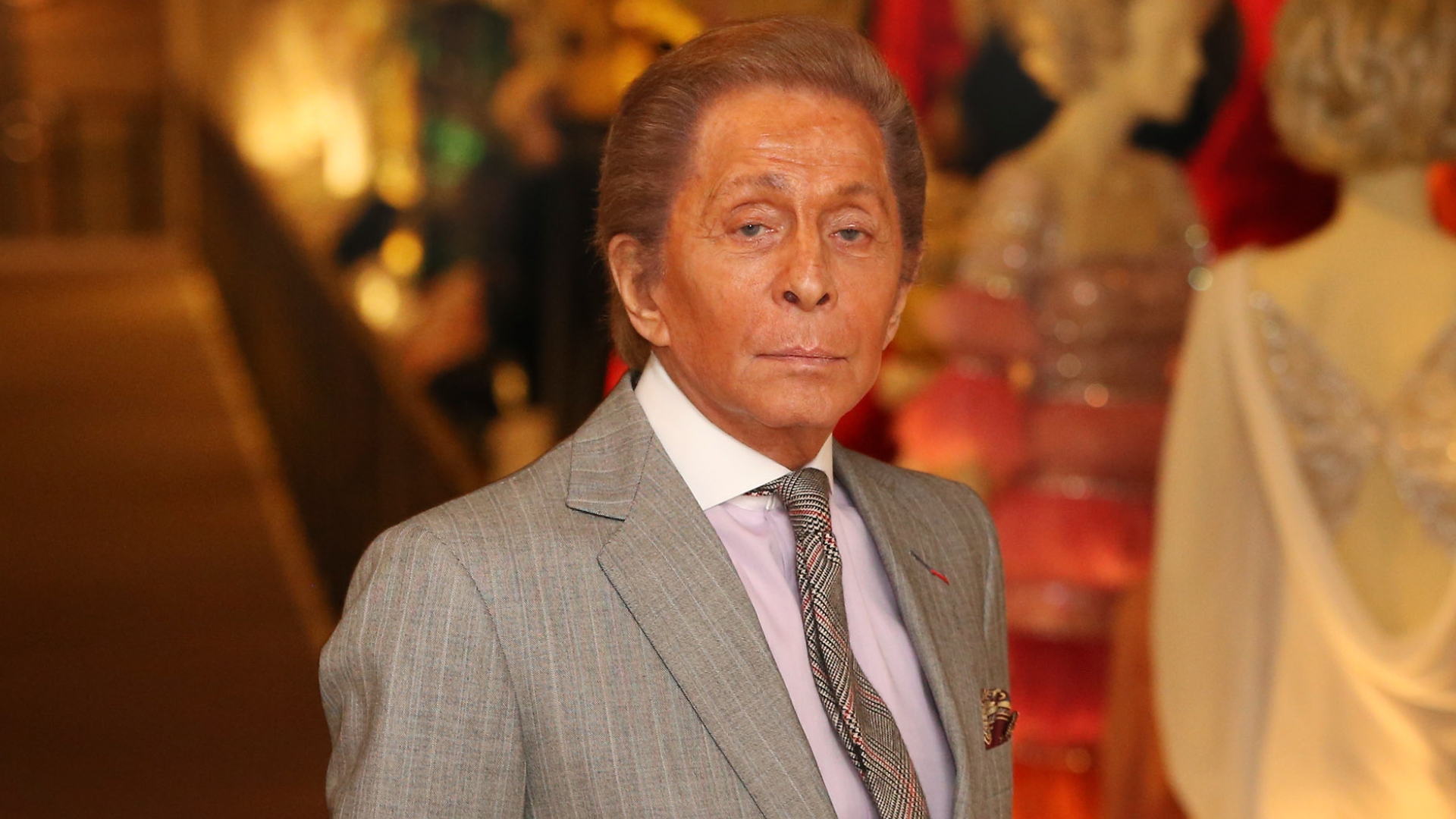 Valentino Garavani poses next to an exhibit