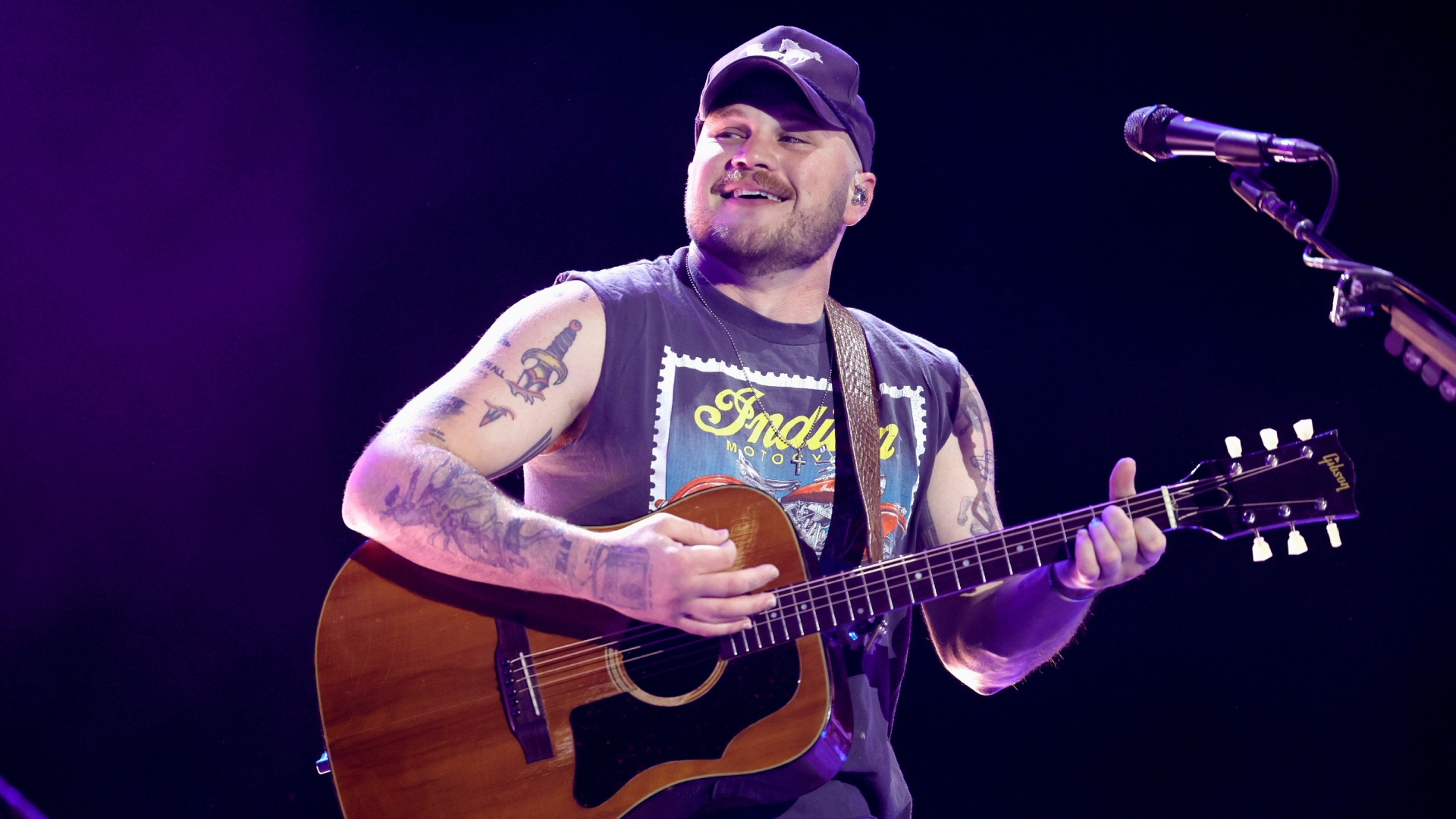 Zach Bryan smiles while performing onstage