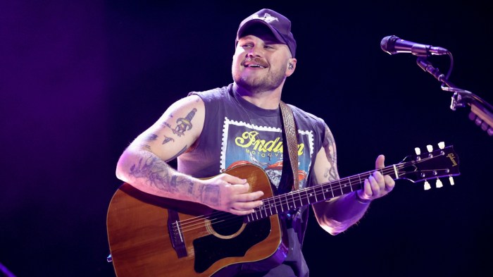 Zach Bryan smiles while performing onstage