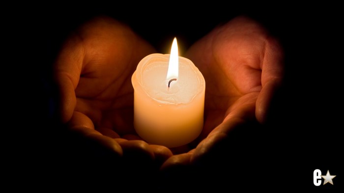 Someone holding a burning candle in their hands