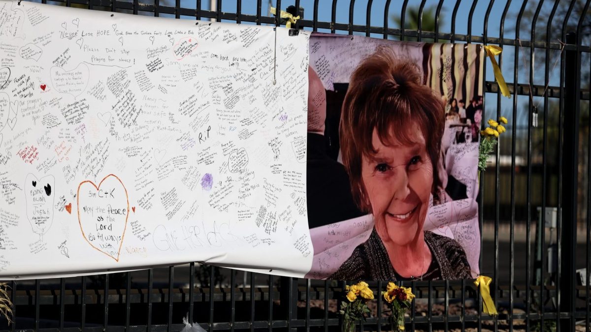 A photograph of Nancy Guthrie is seen on a sign that people can leave messages on