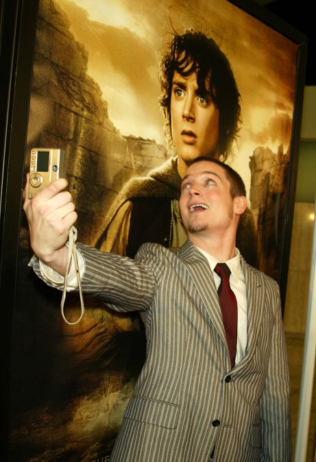 Elijah Wood in front of a The Lord of the Rings poster.