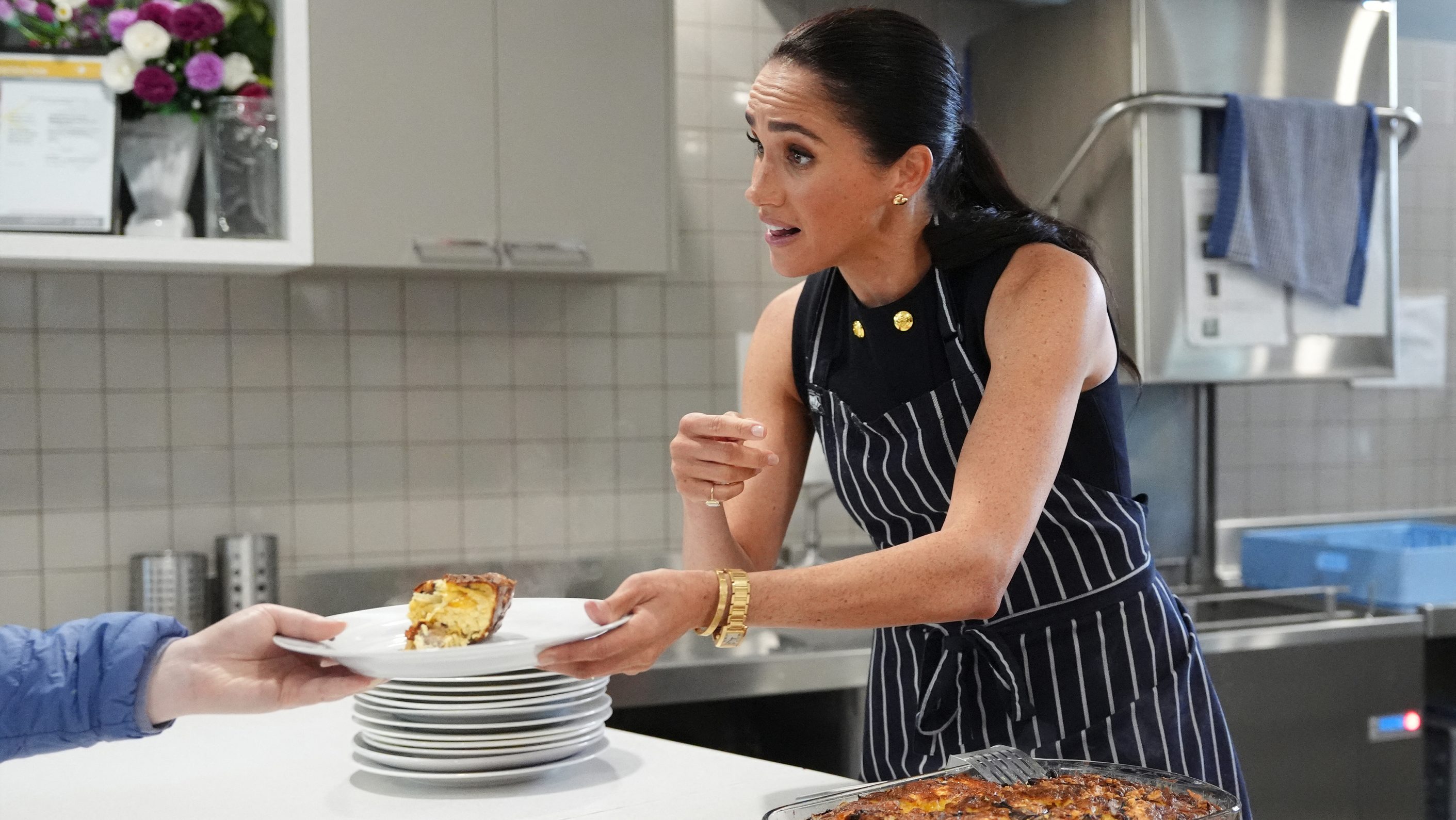 Meghan, the Duchess of Sussex, serves lunch to a resident during a visit at the McAuley Community Services for Women.