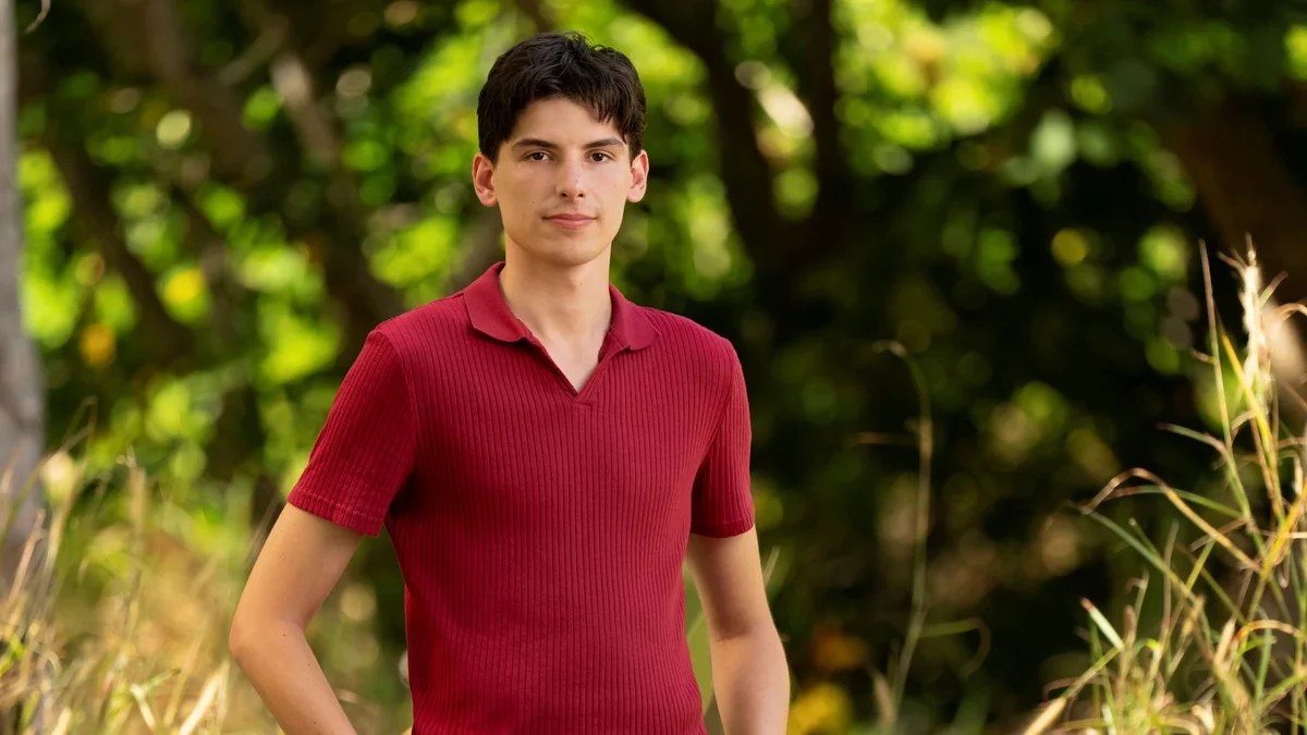 Rizo stands outdoors on “Survivor 50” in a red shirt and khaki shorts
