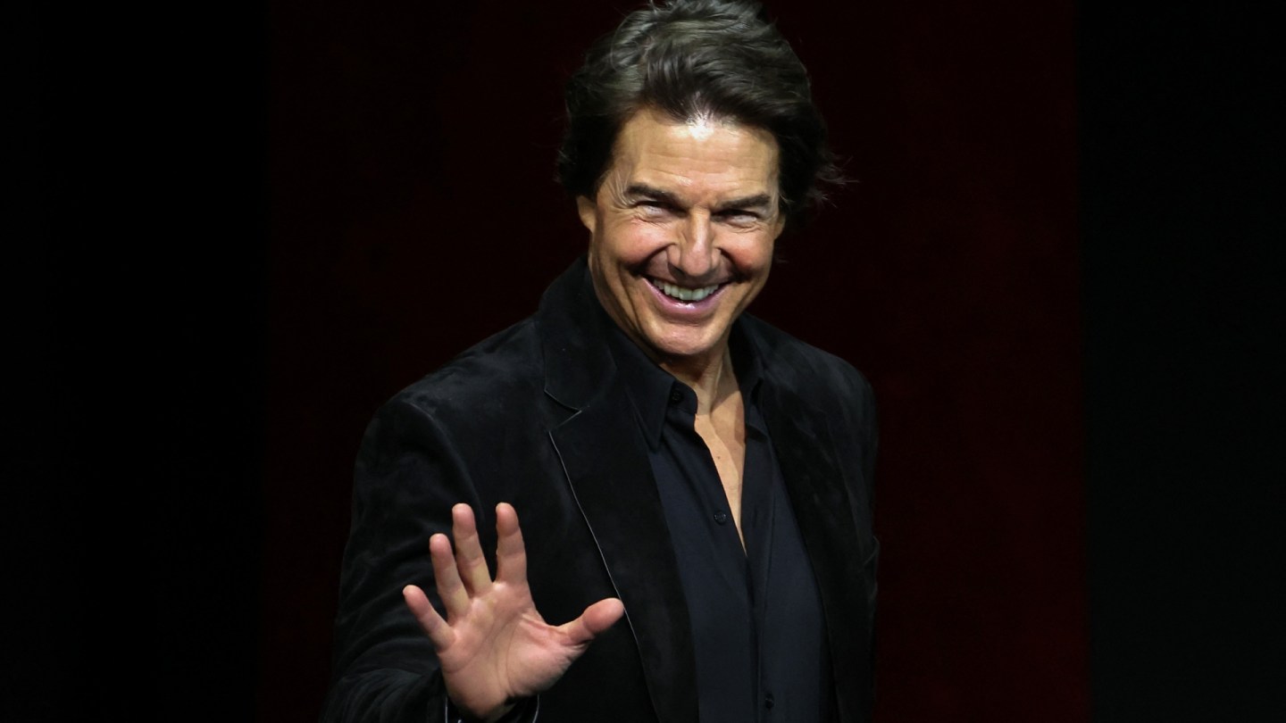 Tom Cruise smiling and waving at an event
