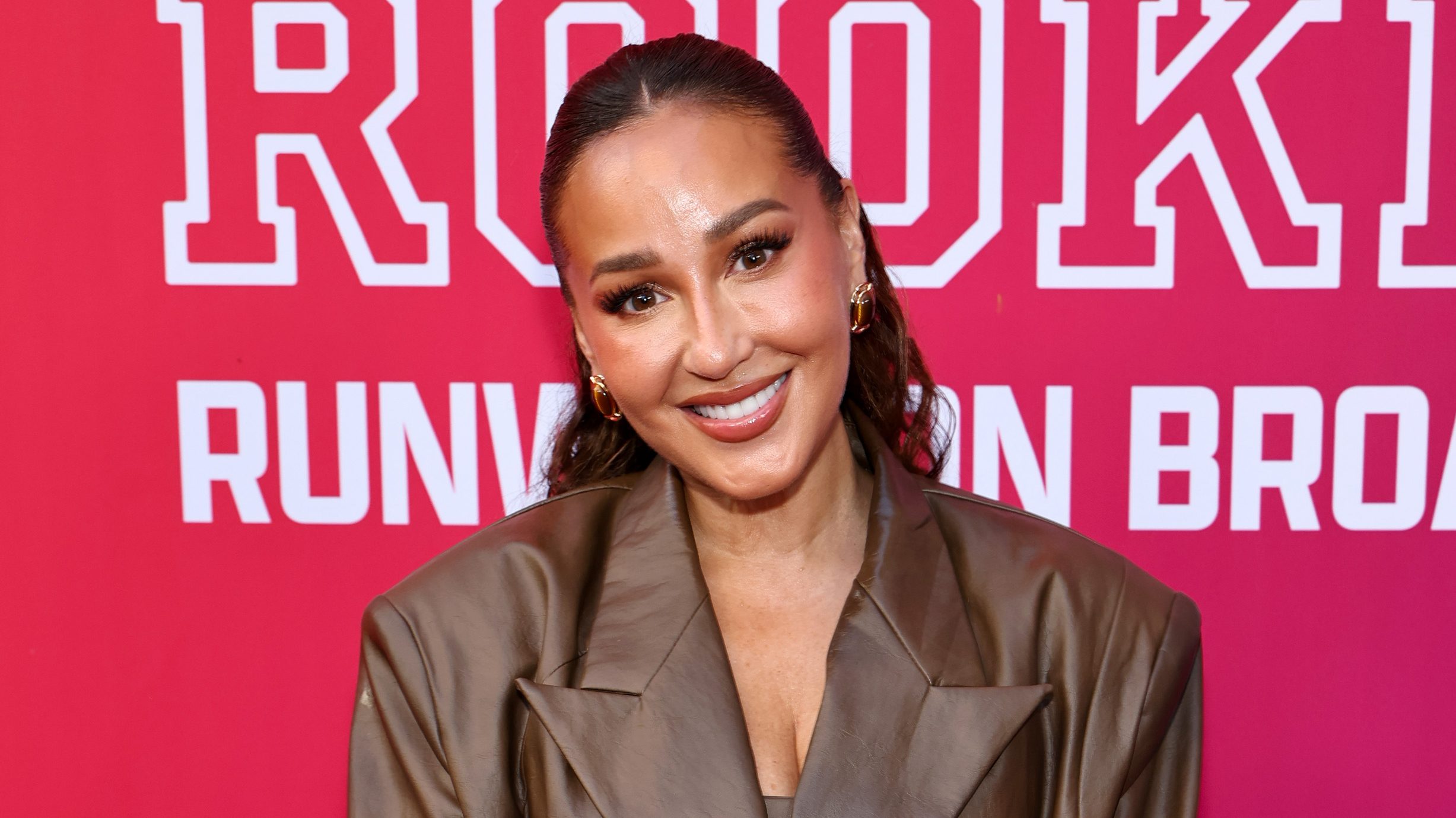 Adrienne Bailon smiling on the red carpet.