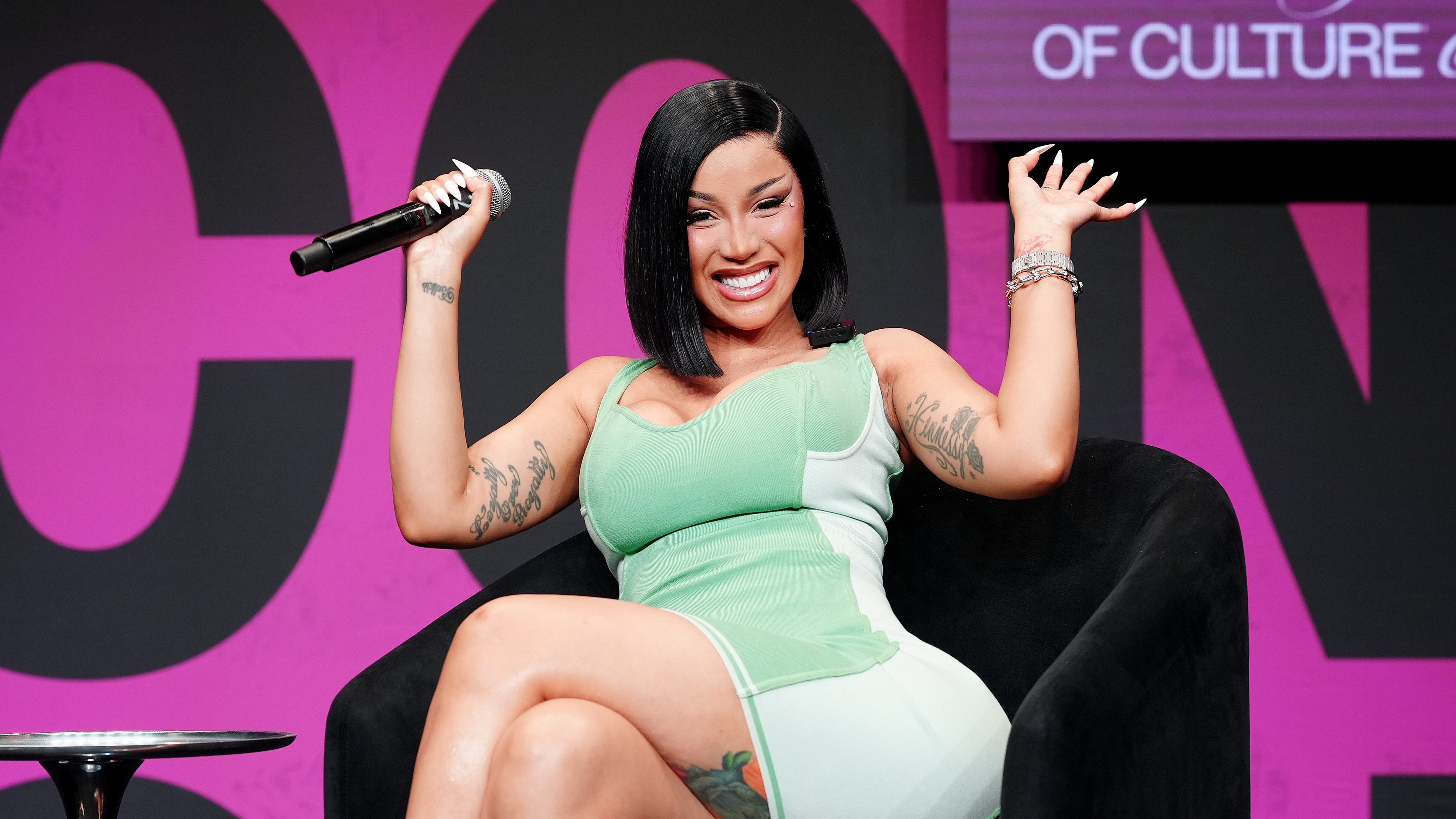 Cardi B in green body con dress on stage