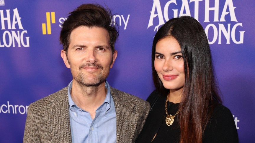 Adam Scott stands next to Frankie Scott in front of an Agatha poster.