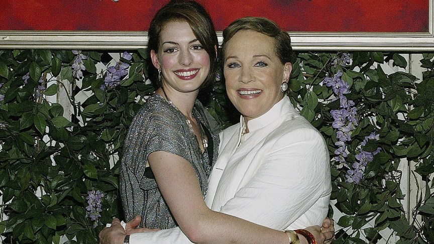 Anne Hathaway and Julie Andrews embrace each other in front a sign for 'Princess Diaries 2'