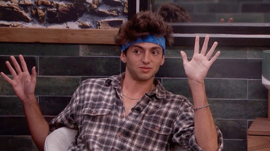 Drew Campbell sits a share in the 'Big Brother' house with his hands in the air.