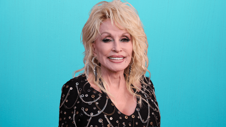 Dolly Parton wears a black and rhinestone dress.