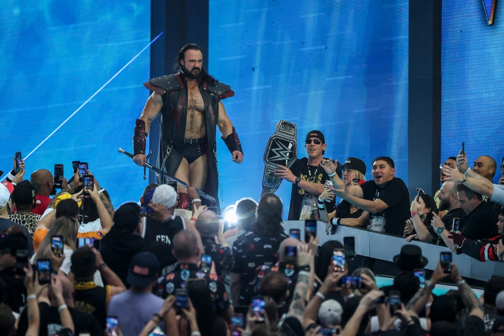 A photo showing Drew McIntyre in a black and red cape, holding a sword.