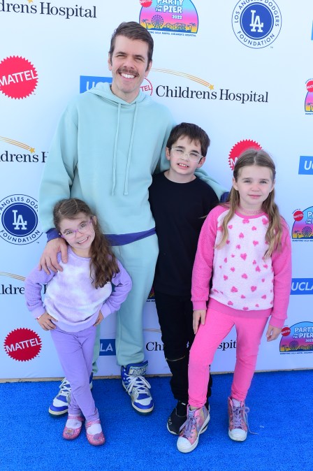 Perez Hilton smiling warmly alongside his three children