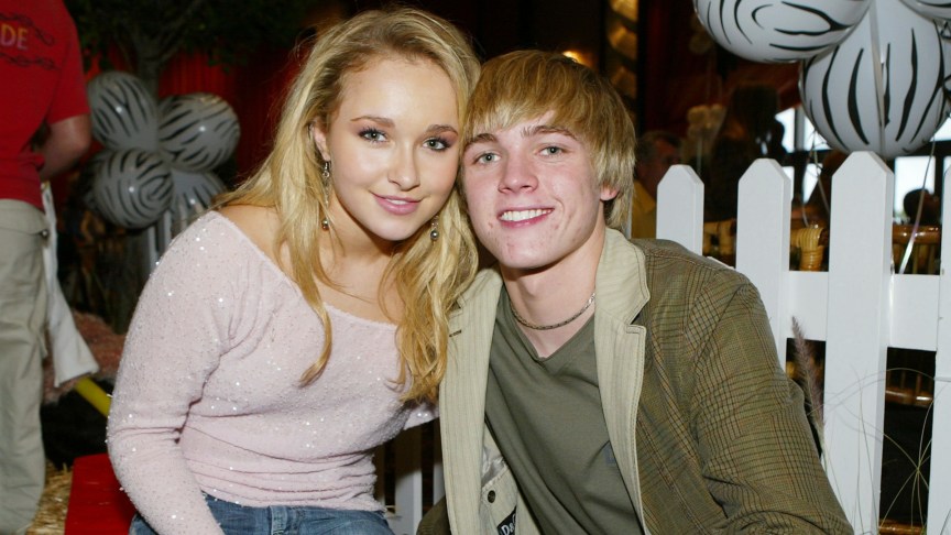Hayden Panettiere and Jesse McCartney smile cheek to cheek in front of a white fence.