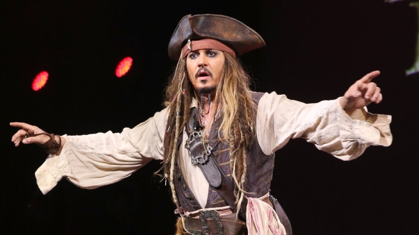 Johnny Depp as Jack Sparrow has his arms out on stage.