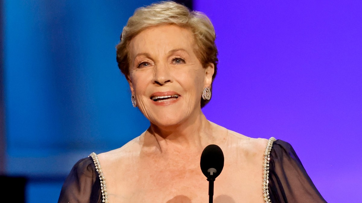 Julie Andrews stands on stage in a blue gown.