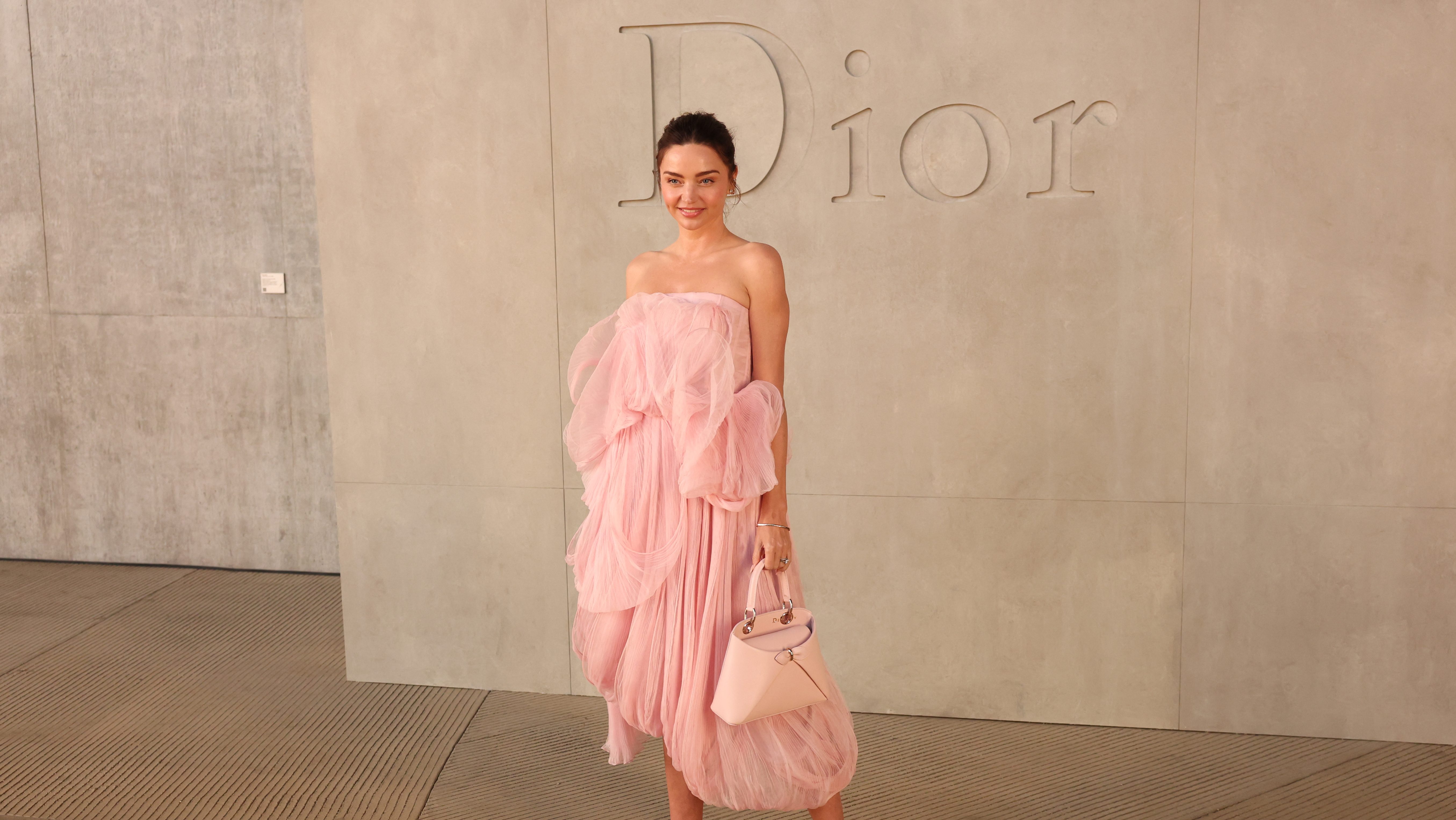 Miranda Kerr poses at Dior in a peach color dress