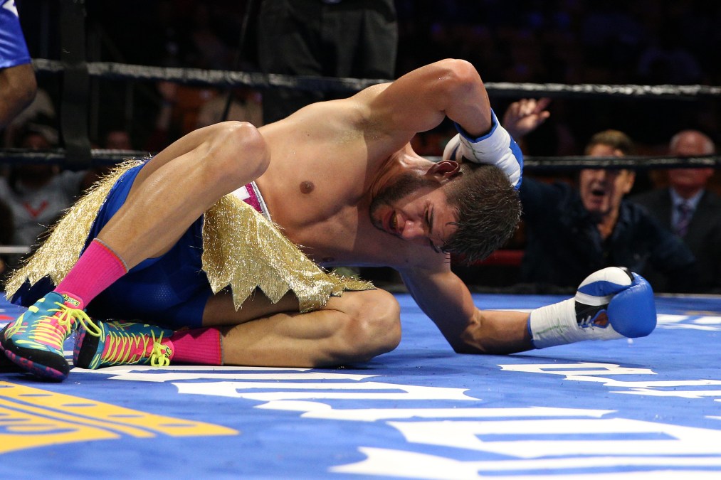 A photo of Prichard Colón on the floor holding the back of his head with a painful expression on his face.