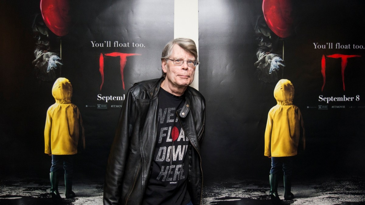 Stephen King stands in front of two "It" posters.