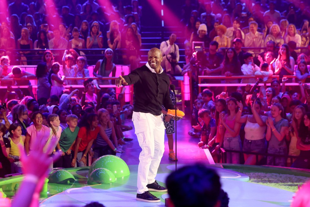 Terry Crews rocking a black button-down shirt and white pants on stage.