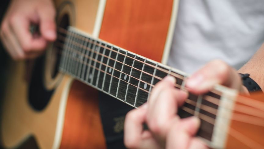 person strumming an acoustic guitar