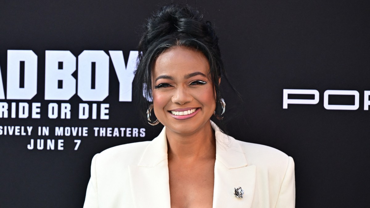 Tatyana Ali smiles in a white blazer.