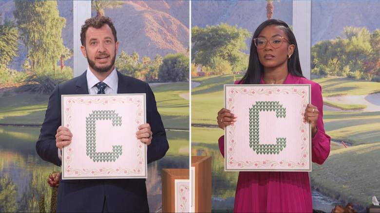 Taylor Brown and Rick Devens hold up a card with "C" on it for a competition.